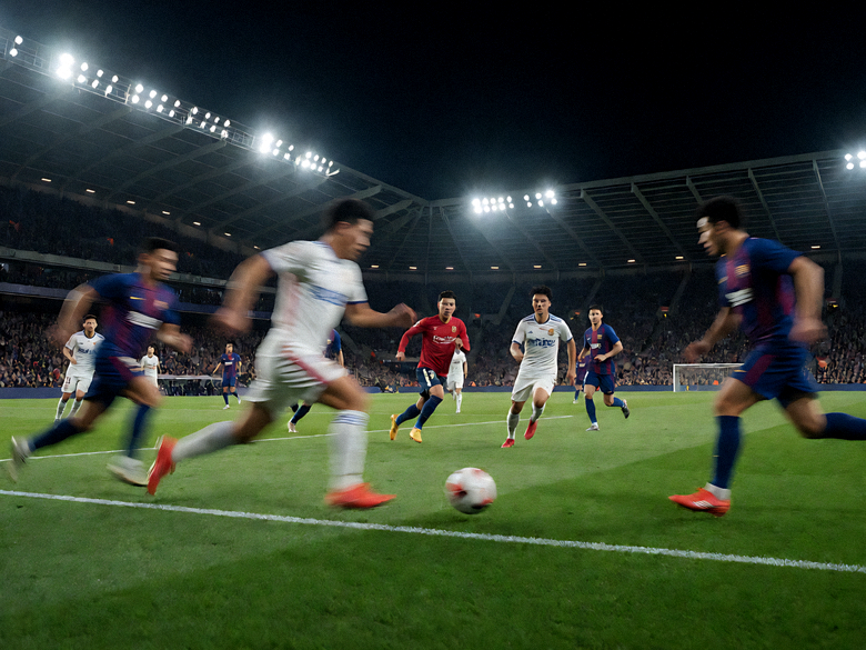夜晚灯光下的足球场全景，看台坐满观众正在进行比赛